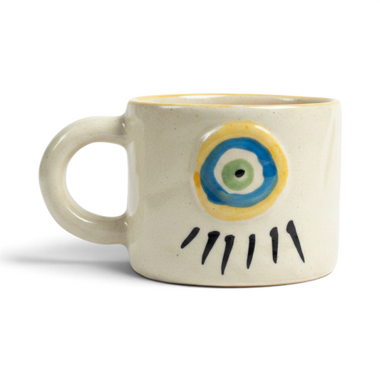 Ayethic Guardian Gaze ceramic mug in ivory clay with a hand-painted blue and green protective eye motif.