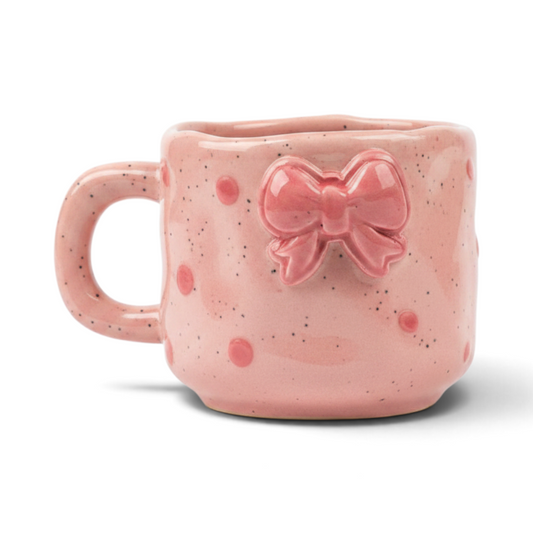 Ayethic pink ceramic mug with a dainty embossed bow, speckled finish, and satin glaze, handcrafted by artisans.